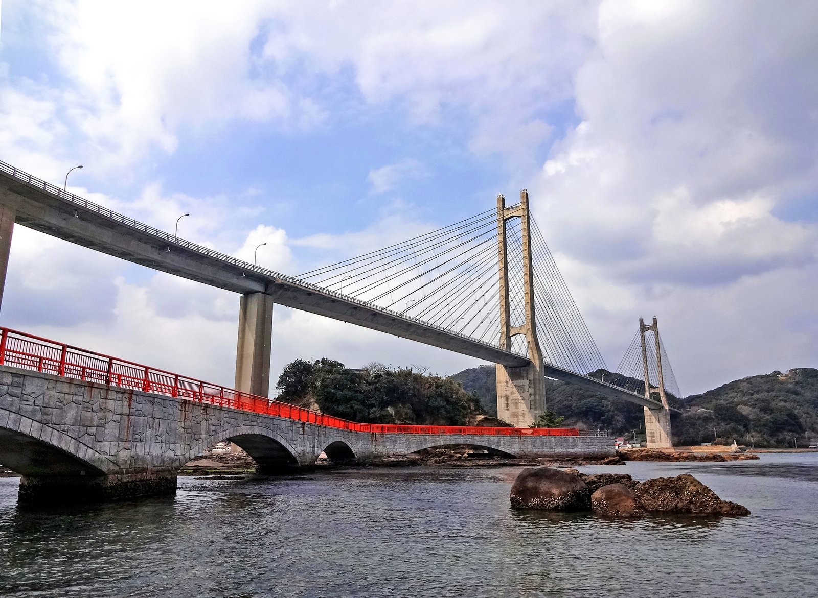 呼子大橋。主塔からケーブルを張った橋が海上にのび、手前には赤い欄干の弁天遊歩道が架かっている。